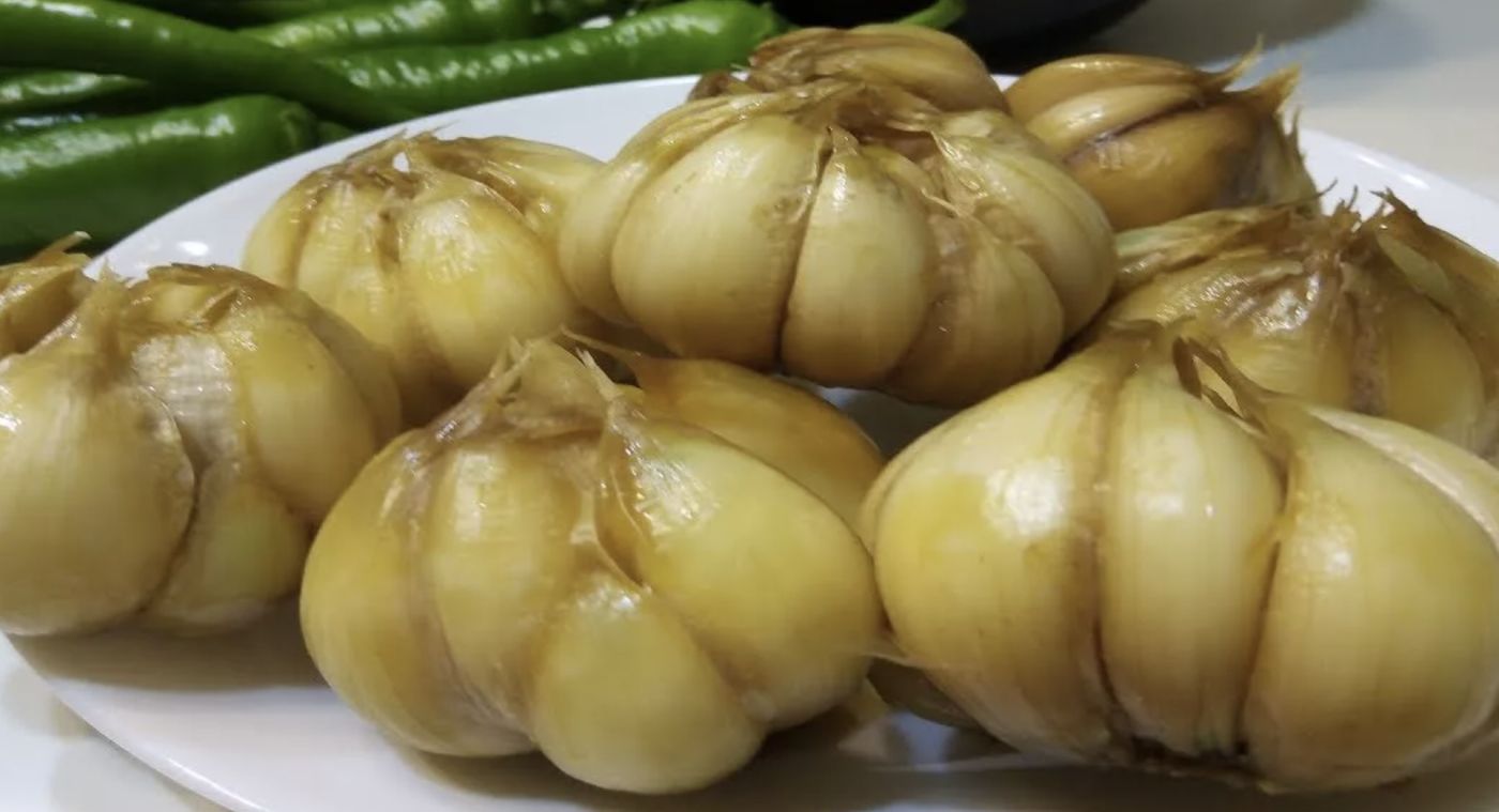 Cabezas de ajo encurtidas en un plato con guindillas